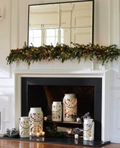 beautiful white snowflake candle lanterns with candles, pinecones and fir branches for a holiday-ready fireplace