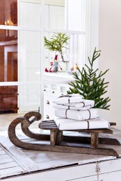 a vintage wooden sleigh with a stack of wrapped gifts and a Christmas tree are great decor for both indoor and outdoor spaces