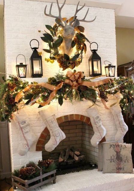 a rustic woodland Christmas mantel with a faux deer head, burlap ribbons, leaves, pinecones, evergreens, a crate with evergreens and pinecones is cozy and lovely