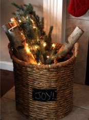 a basket with a chalkboard sign, firewood, evergreens and lights is a pretty rustic decor idea for Christmas, even if you don’t have a fireplace