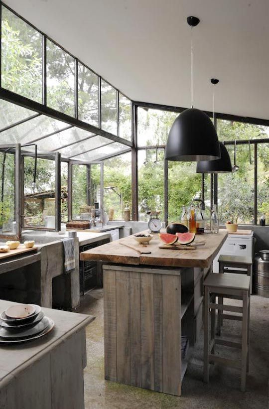 a modern rustic and organic kitchen, almost fully glazed to enjoy forest views and with a series of windows to open the space to this forest
