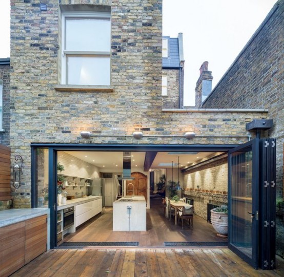 a contemporary white kitchen with sleek cabinets that continues outdoors to the outdoor one and can be opened to it with a folding glass wall