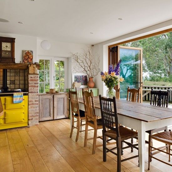 a colorful eclectic kitchen with a glazed folding wall that allows the dining zone to be opened to the garden