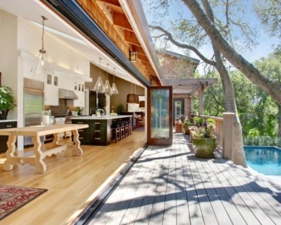 a modern farmhouse kitchen and dining space featuring a glass folding wall that opens them to the pool space and garden and allows fresh air in