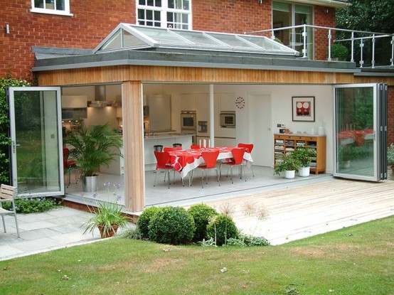 an extension with a kitchen and a dining zone and folding glass walls to open the space to the garden and make indoors and outdoors more connected