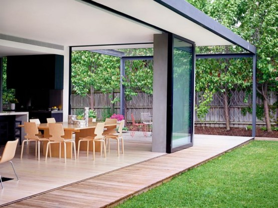 a contemproary kitchen with a dining space and glass walls that can be folded or slided and open the space to the garden completely