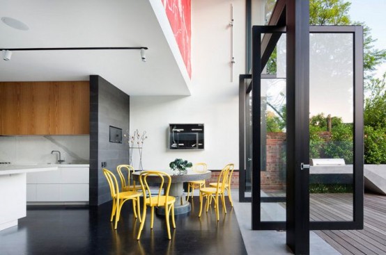 a contemporary kitchen with a bright dining zone and pivot doors that allow to open the space to outdoors