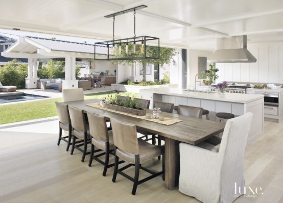 a modern white kitchen and a modern farmhouse dining zone opened to outdoors and the garden with a garage door