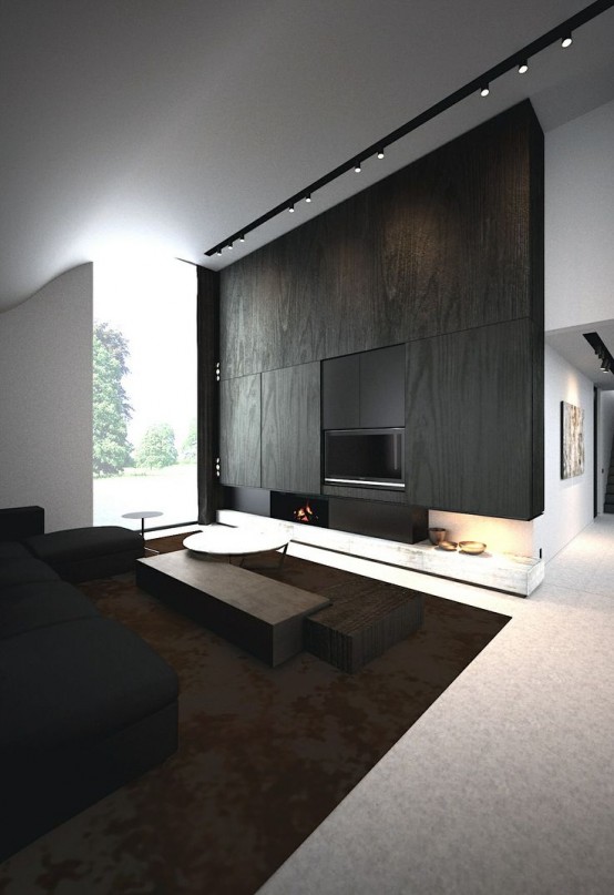 a minimalist living room with a wood clad wall and fireplace, a black sofa and dark stained furniture