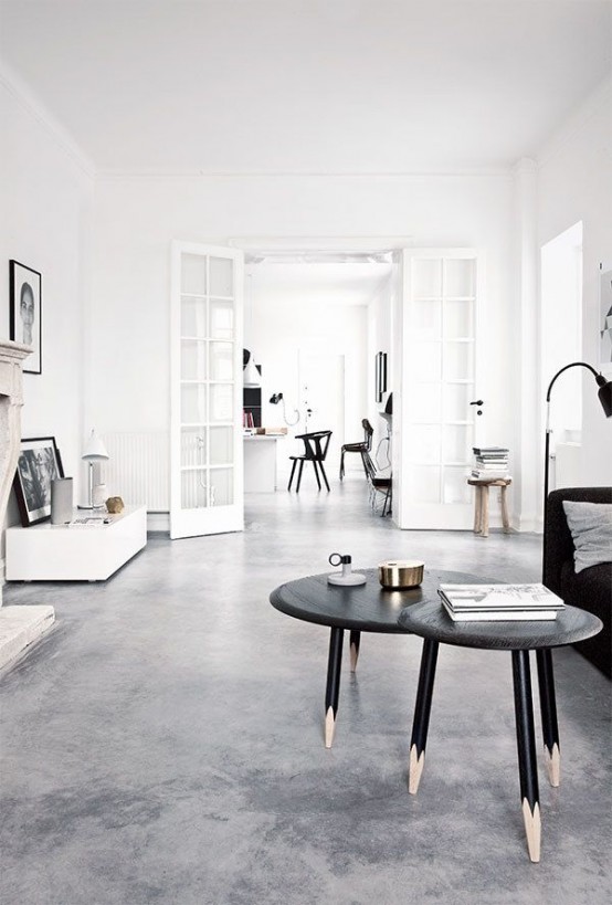 a minimalist meets Nordic living room with a black sofa and coffee tables, white and wooden furniture and a fireplace