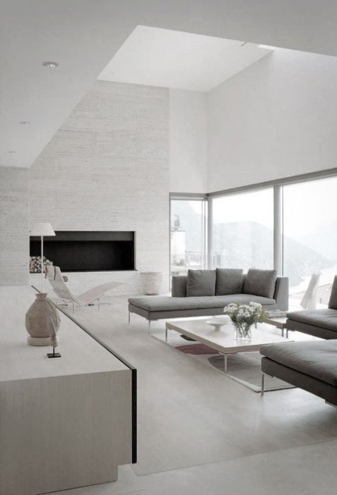 a neutral minimalist living room with a fireplace, grey furniture and a gorgeous view through the windows