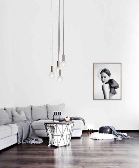 a minimalist living room with a grey sofa, an artwork, a geometric table and pendant lamps