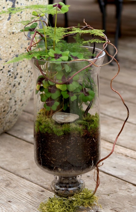 a glass jar with greenery and ferns plus pebbles and vines is a lovely idea for a spring touch in the space