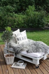 a pallet bed with faux fur and pillows is a great indoor or outdoor daybed that you can DIY