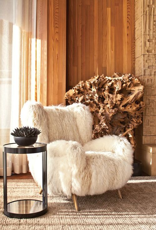 a large white faux fur chair with wooden legs is a stylish piece to integrate into your interior and add coziness to it