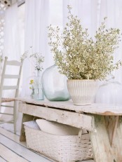a pretty and relaxed space with a whitewashed bench and a whitewashed basket, with potted blooms and bottles is a lovely idea