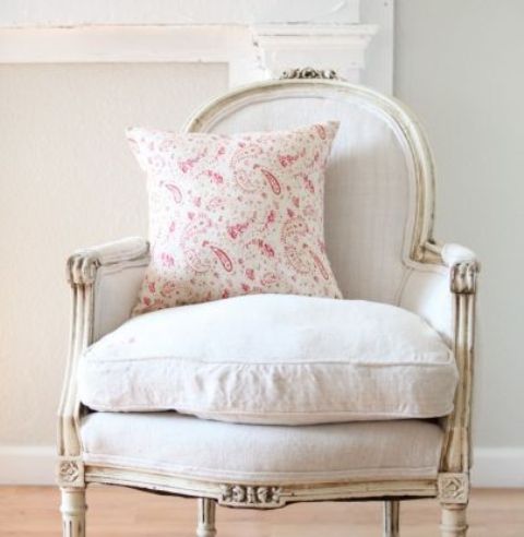 a vintage whitewashed chair with a soft cushion and pink pillow will bring a touch of elegance and chic to the room