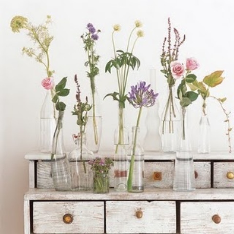 a whitewashed sideboard with bottles and various blooms is a lovely idea for cool summer or spring decor