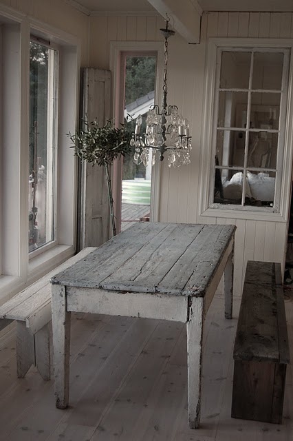 a whitewashed dining space with a shabby chic table and a bench, with a rough wooden bench and a crystal chandelier is a pretty idea to rock