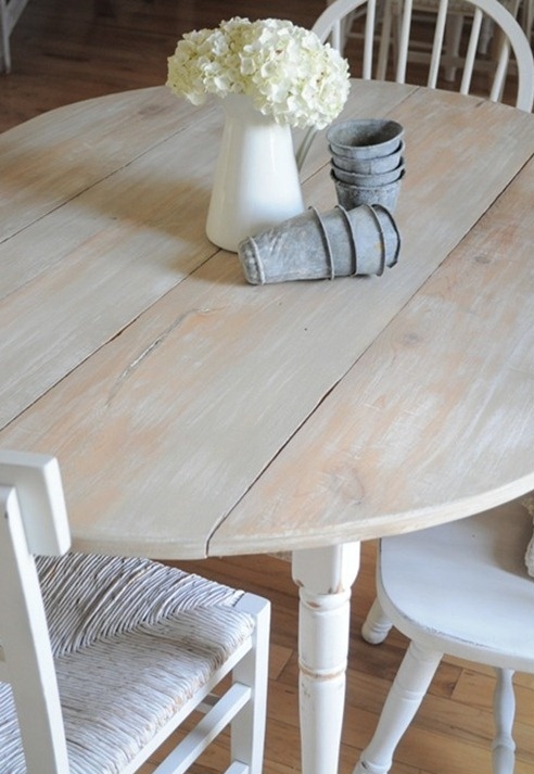 a whitewashed round table and mismatching white chairs is a cool idea for a shabby chic or vintage dining space