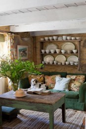 a rustic living room with a green sofa, some shabby chic and rustic furniture and potted greenery