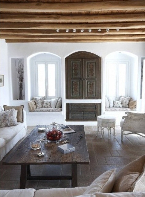 wooden beams on the ceiling, vintage wooden doors with detailing and a dark stained wooden table for a chic ambience