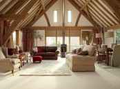 an attic ceiling with beams and a hearth make this open plan living room very cozy and welcoming