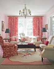 a pretty feminine living room with neutral and printed red seating furniture, printed pillows and curtains, layered rugs and potted plants and lamps