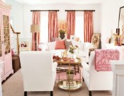 a stylish modern living room with white seating furniture, coral and pink pillows, pink curtains and a pink bookcase, touches of gold and brass for a cooler look