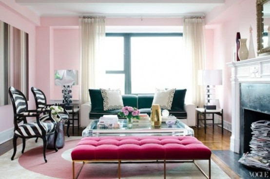 a refined pink living room with a black sofa, zebra print chairs, a fuchsia ottoman and an acrylic table plus a fireplace