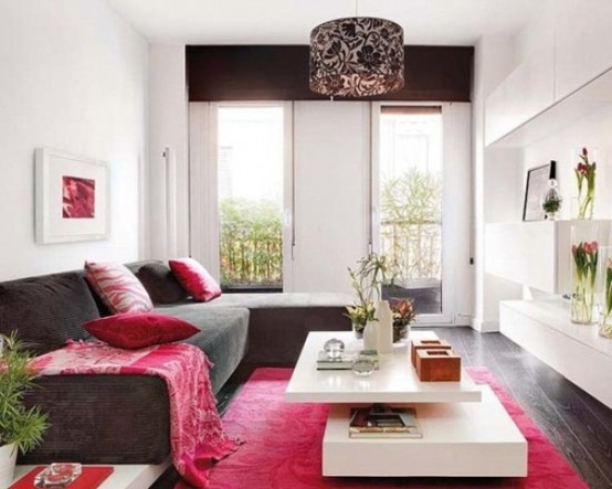 a contrasting and bold feminine living room with a brown sectional and curtains, a hot pink rug and pillows, a tiered coffee table