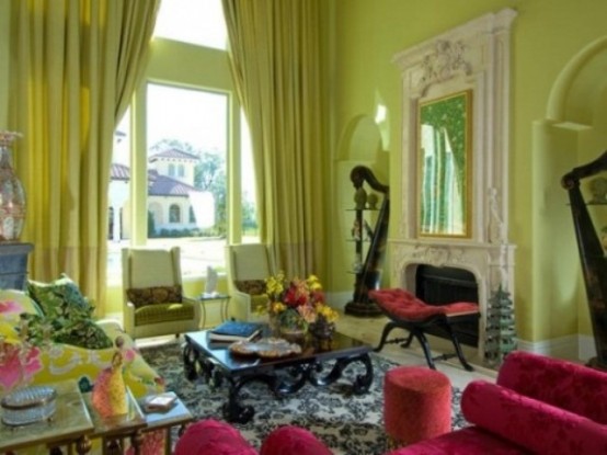 a vintage light green living room with matching curtains, white and green seating furniture, pink poufs and a chair and a vintage fireplace