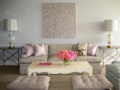 a neutral delicate living room with tan and grey seating furniture, poufs and a low coffee table, blush pillows and an artwork
