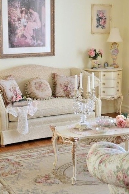 a neutral vintage living room with chic and refined furniture, a low coffee table, a crystal candelabra, floral prints and a vintage artwork