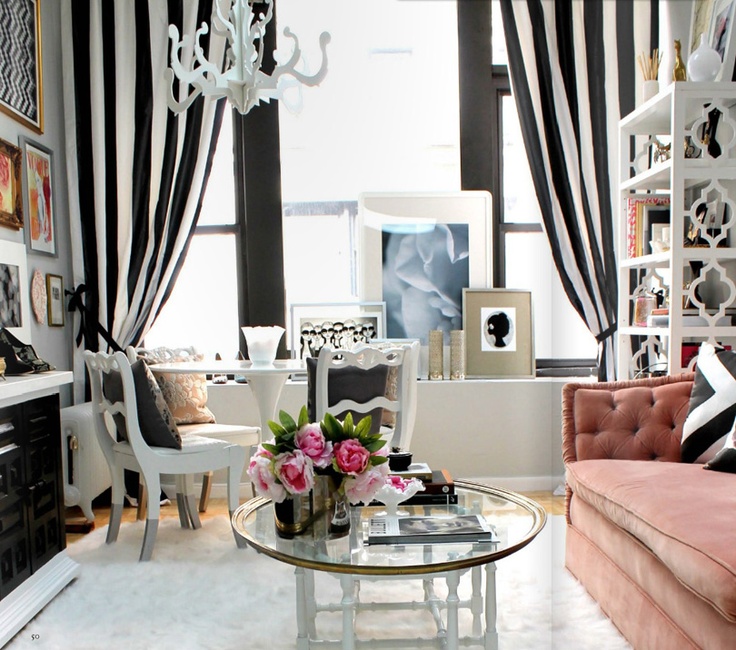 a catchy and contrasting feminine living room in black and white, with striped curtains, a pink sofa, black and white furniture and a refined crystal chandelier