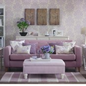 a delicate lilac living room with floral printed wallpaper, a lilac sofa, a matching ottoman, a striped rug and a floral gallery wall