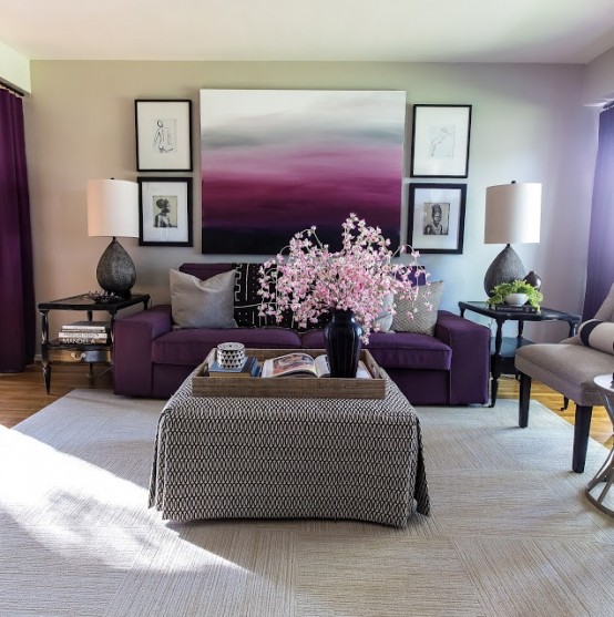 a bright living room with with a purple sofa, grey chairs, an ottoman, a gallery wall and table lamps