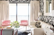 a chic girlish living room with black and white floral print wallpaper, pink chairs, a white sofa and a striped loveseat and greenery