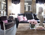 an eclectic living room with rough wood, black leather furniture, pink pillows and blooms and black curtains is amazingly chic