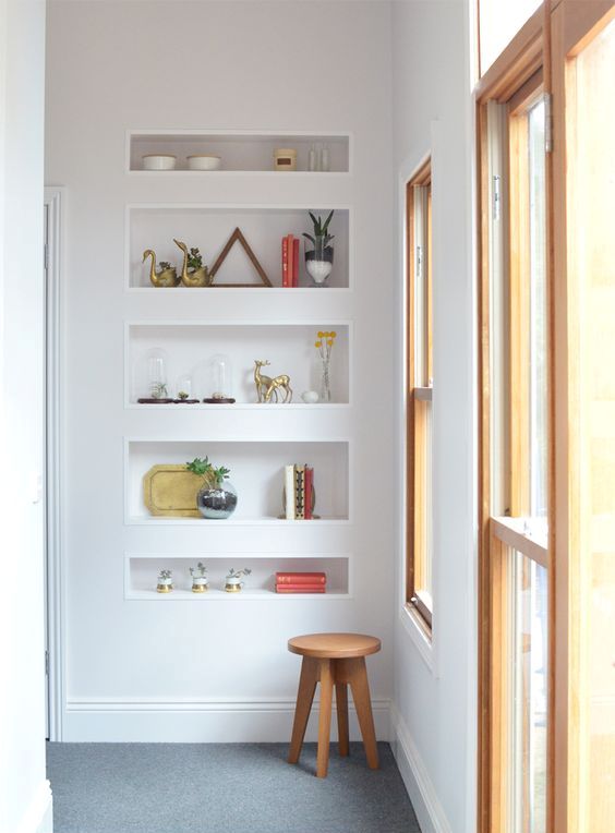 a wall with a series of sleek niche shelves is a cool solution to store and display things in a modern way