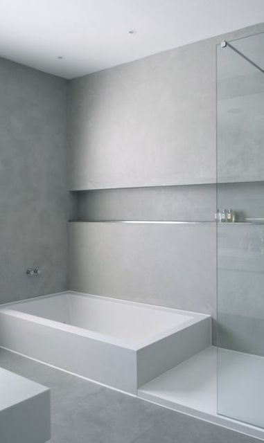 a minimalist neutral bathroom with sleek walls and a large niche shelf to store various stuff, with a bathtub and a shower space