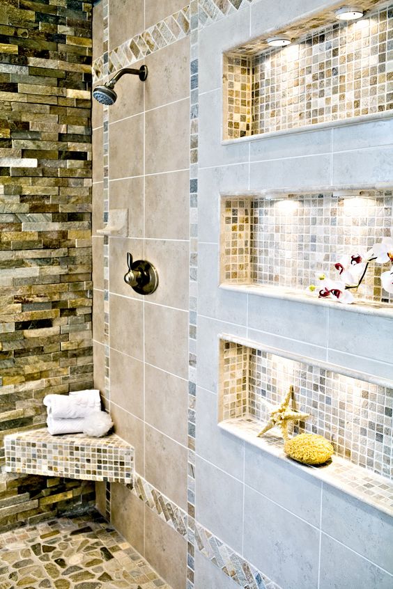 a stylish and cozy bathroom with various types of tiles and niche shelves with additional light to store shampoos, balms and various other stuff