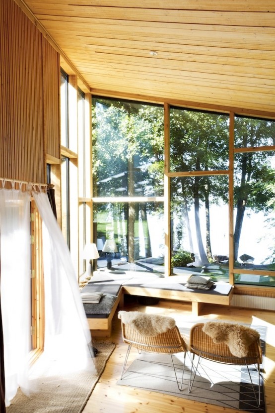 a beautiful and natural-looking sunroom with a Nordic feel, with much sunshine, an upholstered corner bench, wicker furniture and printed textiles