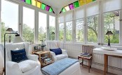 a white Nordic sunroom with vintage furniture, stained furniture, printed pillows and colorful mosaic decor to add a bit of color and interest to the space