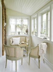 a vintage neutral Scandinavian sunroom with sophisticated furniture, vintage chandeliers, neutral textiles