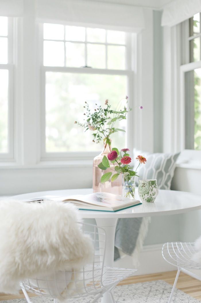 an airy white Scandinavian sunroom with elegant white furniture, metal chairs and printed textiles