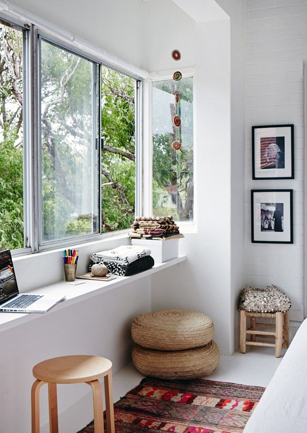 a beautiful Scandinavian space with a windowsill desk, jute poufs, a bold printed rug and lovely furniture