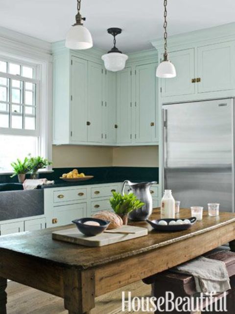 a beach kitchen with light aqua cabinets, black stone countertops and a shabby stained wood table as a kitchen island