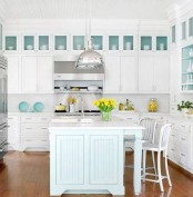 a lovely coastal kitchen with white shaker cabinets, aqua backing of cabinets and tableware, a pale blue kitchen island