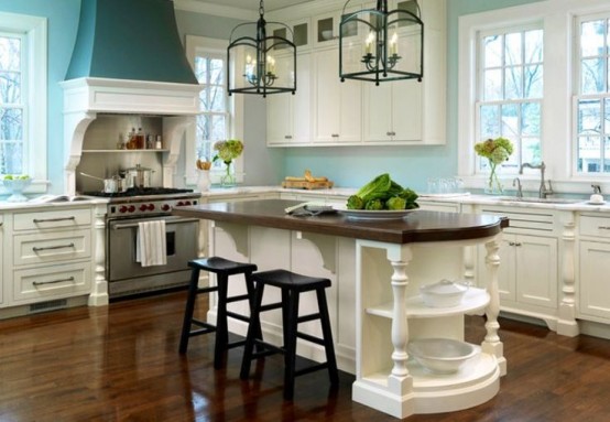 a classic beach kitchen with white shaker cabinets, white stone countertops, light aqua walls and a teal hood, a vintage kitchen island with a dark stained countertop
